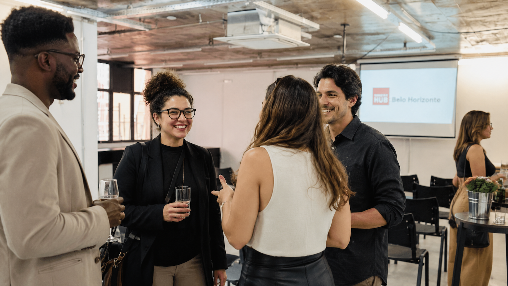 Salão de eventos com pessoas em um evento corporativo conversando em pé.